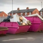Pink skips in different sizes with house clearance waste at a Greater Manchester skip hire yard.