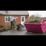 Small pink skip half filled with soil on a Manchester driveway during garden excavation.