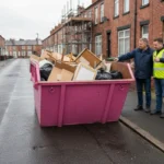 Pink skip safely filled below the rim with renovation waste on a Manchester residential driveway.