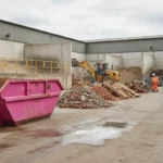 Pink skip waste being sorted for recycling at a Manchester waste transfer facility.
